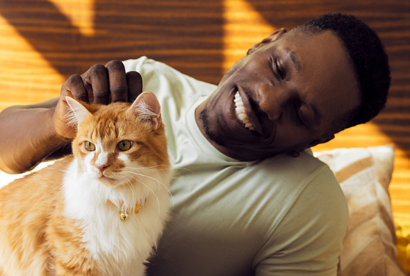 A man smiling and petting his cat